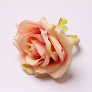 Macro detail of artificial rose napkin ring with pink-orange gradient petals and woven band