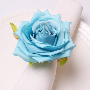 Detail of light blue artificial rose napkin ring on white napkin for wedding table setting
