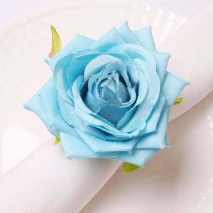 Detailed view of light blue artificial rose napkin ring with leaves on white linen
