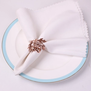 Rose gold acorn and leaf napkin ring set on a white scalloped plate for table decor