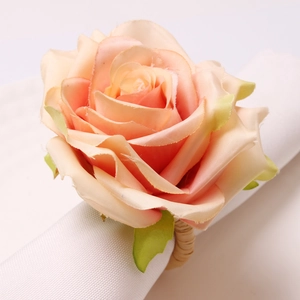Elegant champagne rose napkin ring with woven rattan base on white cotton fabric