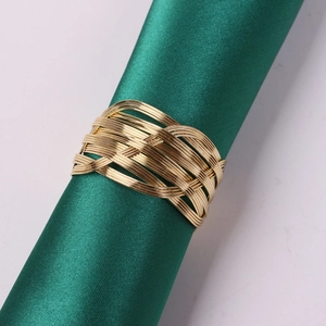 Dettaglio portatovagliolo in filo metallico intrecciato dorato su tessuto di raso verde
