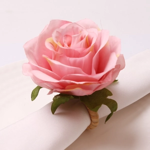 Close-up of pink silk rose napkin ring with green leaves and woven rattan band detail