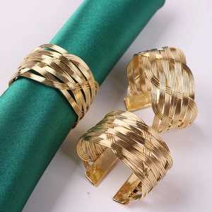 Dettaglio macro di portatovaglioli in filo d'oro intrecciato su raso verde elegante
