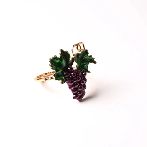 Detailed shot of golden napkin ring featuring purple grape cluster and green enamel leaves