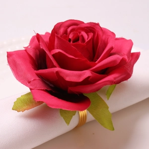 Close-up of red fabric rose napkin ring with gold spiral metal base on white fabric