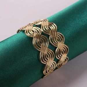 Macro view of golden woven napkin ring with intricate wave pattern on silk stand