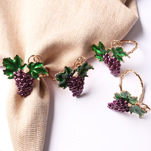 Detailed view of four purple grape napkin rings with green leaves on golden bands