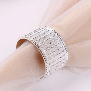 Close-up of silver napkin ring with linear bead texture on elegant champagne fabric