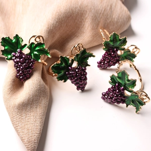 Detail of gold napkin rings with purple grape design and green enamel leaves for table decor