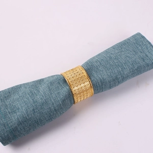 Macro detail of golden metal napkin ring with embossed dot texture on blue fabric