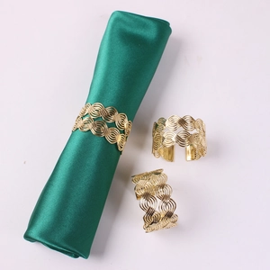 Macro shot of gold metallic napkin rings featuring a woven lantern design on dark silk