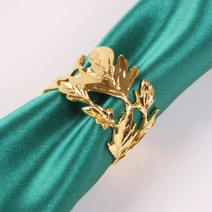 Detail of golden maple leaf napkin ring on a green satin fabric with hollow design