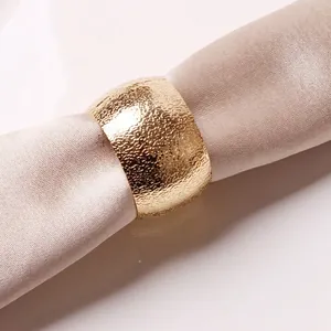 Rond de serviette doré martelé élégant sur une serviette en soie beige raffinée