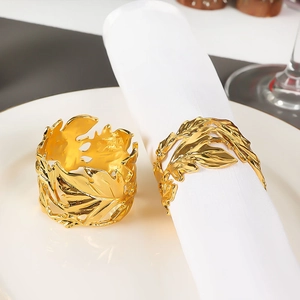 Detail of golden maple leaf napkin rings showing hollow design on white dinnerware