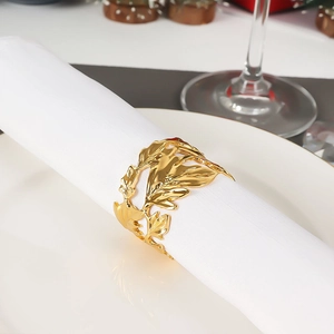 Macro detail of a hollow leaf napkin ring in golden finish on a white table setting