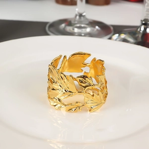Detailed view of golden leaf napkin ring featuring intricate hollow metal texture on plate