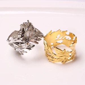 Macro detail of gold and silver hollow leaf napkin rings with intricate vein textures
