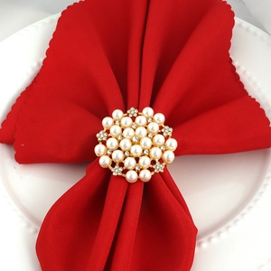 Macro view of golden napkin ring with sparkling pearls and diamonds on red napkin