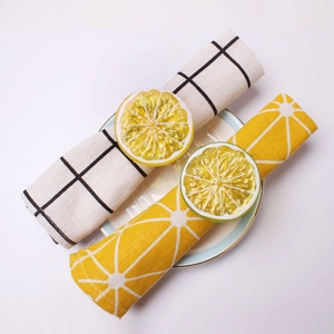 Detailed view of realistic lemon and orange slice napkin rings on patterned napkins