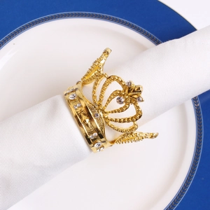 Close-up of golden crown napkin ring with rhinestones on a white linen napkin