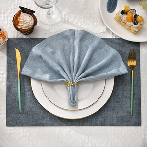 Elegant gold Love metal napkin ring on blue linen napkin with white ceramic plates