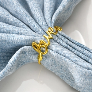 Elegant gold LOVE letter metal napkin ring placed on light blue linen fabric background