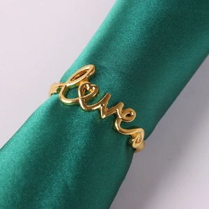 Macro shot of gold metal Love napkin ring on green silk roll for table decor