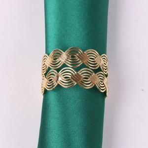 Golden woven wavy napkin ring with hollow design on green silk napkin background