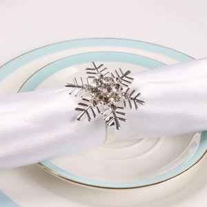 Detailed view of silver snowflake napkin ring with rhinestones on a white satin cloth