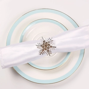 Macro view of silver snowflake napkin ring with brown rhinestones on white fabric