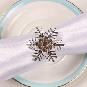 Silver snowflake napkin ring with crystals on white napkin over elegant ceramic plate