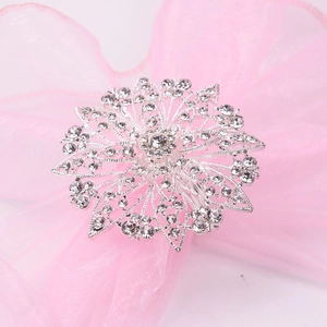 Silver snowflake napkin ring with sparkling crystals on pink organza ribbon background