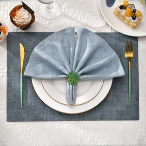 Green palm leaf napkin ring set with blue linen napkin on a white lace tablecloth