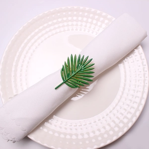 Tropical palm leaf napkin ring with green enamel finish on a white cloth napkin