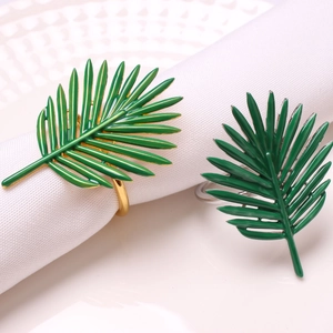 Detail of green leaf napkin ring with palm frond texture on a white cloth napkin