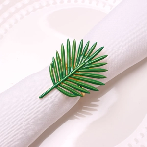Detail of green leaf napkin ring with gold edges on white fabric napkins