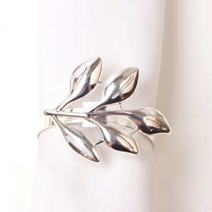 Detail of silver leaf napkin ring with a polished mirror finish on white fabric