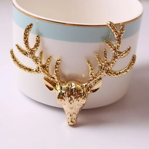 White ceramic decorative jar with gold deer head relief and blue border trim
