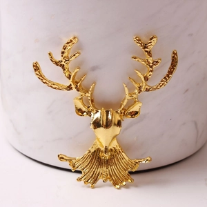 Macro shot of a luxury gold deer head ornament with detailed antlers on marble stand