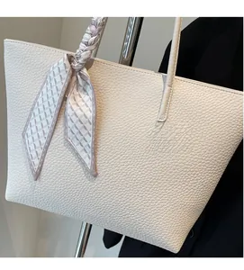 Close-up of cream tote bag with lychee texture and a decorative printed silk scarf handle