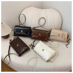 Sélection de sacs à main rétro en noir, marron et blanc posés sur un canapé moelleux