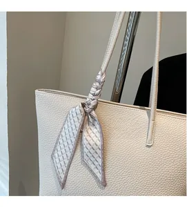 Detail of beige tote bag with lychee grain leather and decorative geometric silk scarf