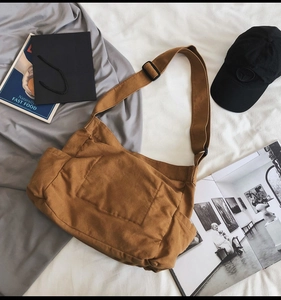 Detail of a brown canvas messenger bag with large front pocket and adjustable strap