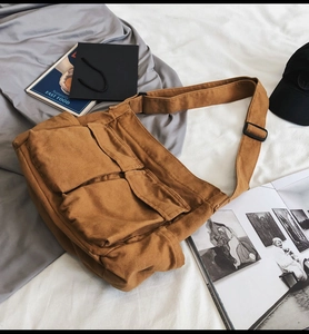 Detail of brown canvas crossbody bag featuring functional large front flap pockets