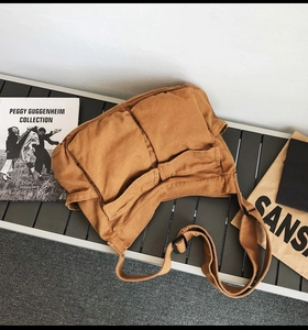 Detailed view of brown canvas messenger bag with double pockets and adjustable strap