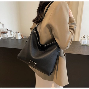 Detail of black pebbled leather tote bag with silver rivet metal plaque decoration