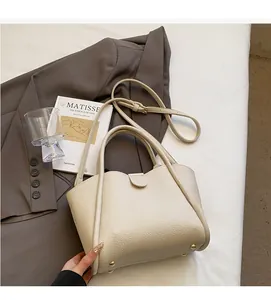 Detail der cremeweißen Beuteltasche aus Leder mit Wellenkante und goldenen Bodennägeln