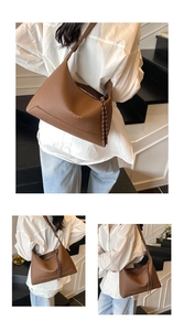 Detail of lychee pattern leather and bicolor woven zipper puller on brown tote bag