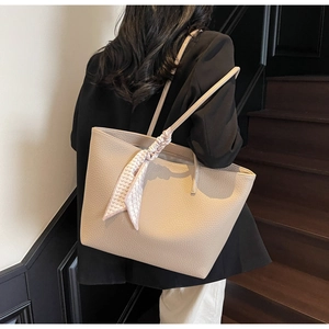Detail of beige tote bag with litchi grain texture and a decorative heart print scarf